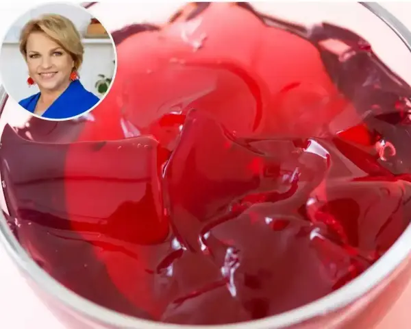 Kobieta w niebieskiej marynarce uśmiecha się obok miseczki z galaretką. Dowiedz się, ile tężeje galaretka, by cieszyć się deserem!
