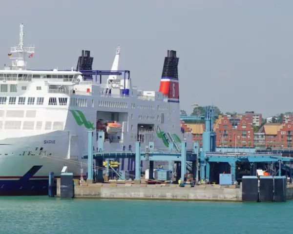 Prom Skania cumuje przy nabrzeżu. Statek pasażerski z zielonymi akcentami i czerwonymi kominami czeka na załadunek.