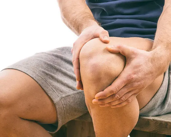 Mann hält schmerzendes Knie. Schmerzen beim Knien auf hartem Boden sind deutlich zu sehen.