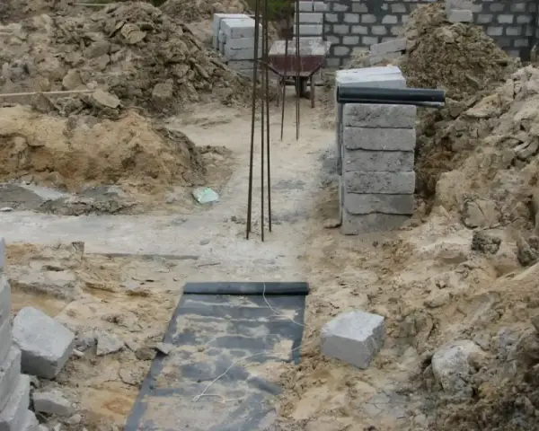 Wykonano wykopy pod fundamenty. Widać zbrojenie, betonowe bloczki i ziemię.