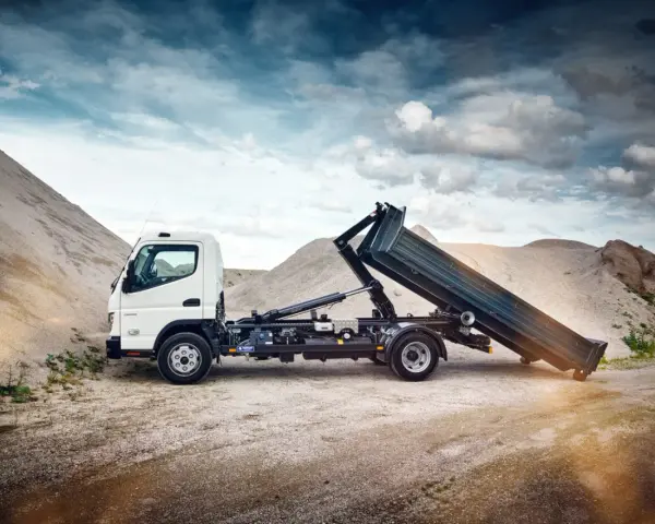 Biały Mitsubishi Canter z podniesioną skrzynią ładunkową na tle żwirowych hałd.