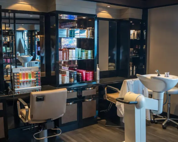 Salon fryzjerski gotowy na klientów. Widać fotele, umywalki i półki z kosmetykami. Dbałość o dezynfekcję w salonie fryzjerskim to podstawa.