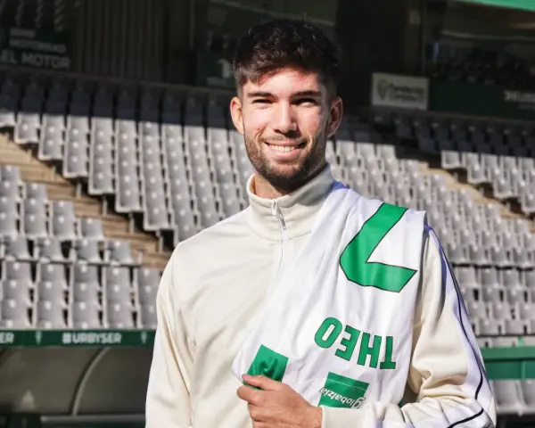 Théo Zidane sonríe con una bufanda del equipo en el estadio.