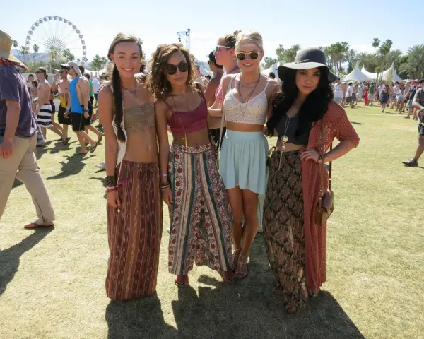 Cztery dziewczyny w letnich strojach pozują na tle festiwalu. W tle widać diabelski młyn. Ile trwa Coachella? Zwykle dwa weekendy.