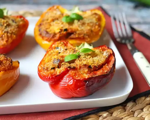 Peperoni ripieni al forno, un classico delle ricette con peperoni, serviti su un piatto bianco con una forchetta.