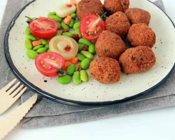 Falafel kontra kotlety sojowe: chrupiące kulki falafela i soczyste pomidorki z edamame na talerzu.
