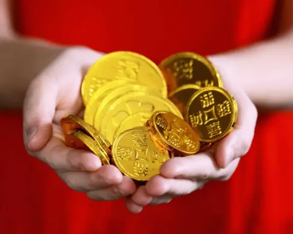 Hände halten einen Haufen glänzender Goldmünzen. Das ist ein schöner Gedanke, wann Urlaubsgeld!
