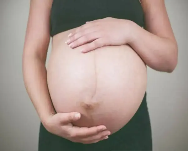 Kobieta w ciąży delikatnie głaszcze brzuch, zastanawiając się, jak pobudzić ruchy dziecka w brzuchu.