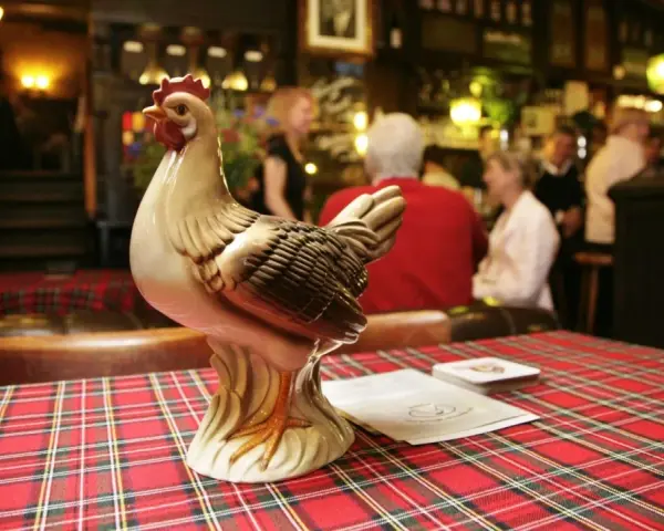 Keramikhähnchen auf kariertem Tisch in uriger Berliner Kneipe.