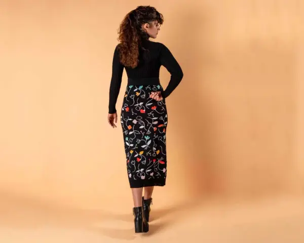Mujer con falda lápiz negra estampada con flores de colores. Un ejemplo de los diversos tipos de faldas.