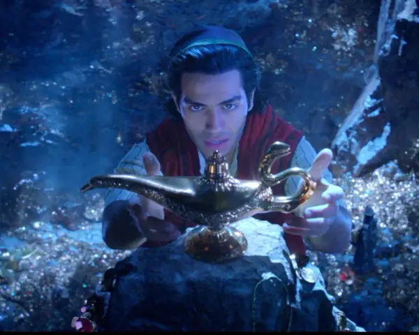 Aladyn, w mrocznej jaskini pełnej skarbów, trzymając magiczną lampę.