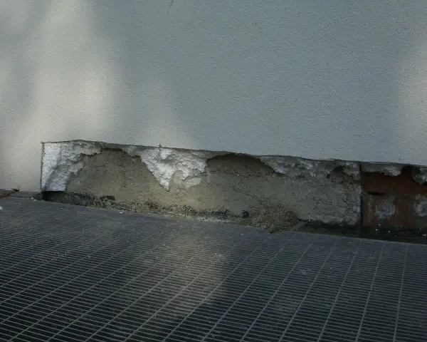 Deterioramento di un muro con esposizione di materiale isolante in eps alta densità e grata metallica sottostante.