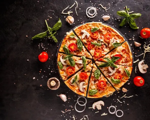 Pyszna pizza z pomidorkami, pieczarkami i bazylią. Zastanawiasz się, ile kcal ma pizza? To zależy od składników!