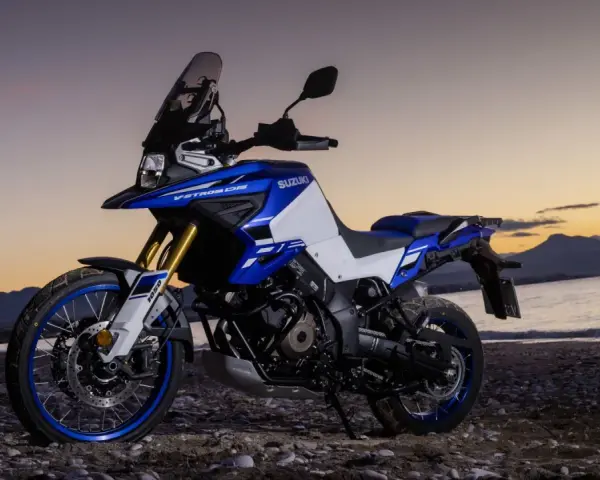 Suzuki V-Strom 1050 DE blu e bianca su una spiaggia al tramonto. Le opinioni su questa moto sono unanimi: avventura pura.