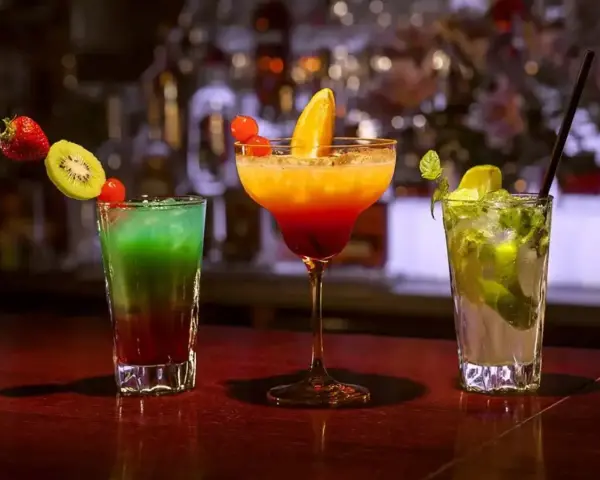 Kolorowe drinki przepisy: zielony, pomarańczowo-czerwony i zielony z miętą, ozdobione owocami. Idealne na letnie wieczory.