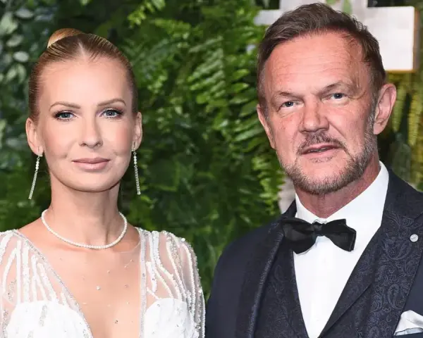 Cezary Pazura z żoną Edytą na ściance. Ona w białej, zdobionej sukni, on w eleganckim garniturze.