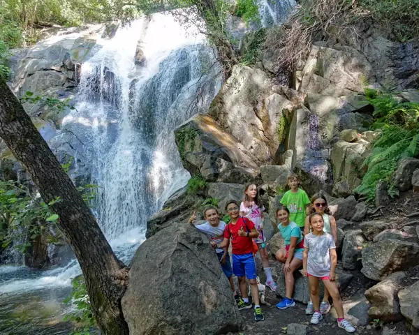 Niños exploran la Garganta de las Nogaleas, disfrutando de una cascada y la naturaleza.