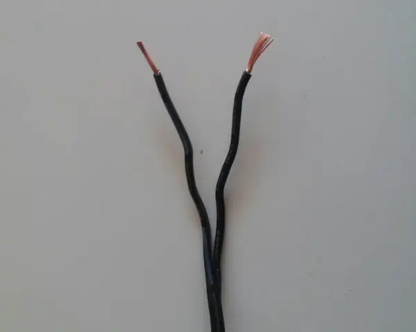 Dwa czarne przewody elektryczne rozchodzą się, odsłaniając miedziane końcówki. Czy czerwony to plus czy minus?