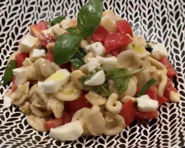 Orecchiette alla crudaiola con pomodorini, mozzarella e basilico fresco, un piatto estivo colorato e saporito.
