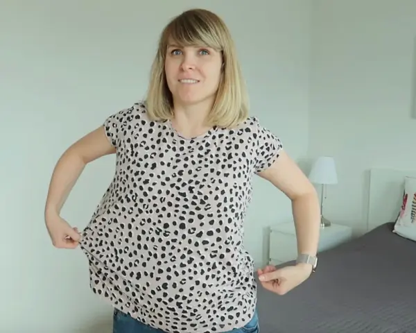 Kobieta pokazuje, jak zwęzić bluzkę na dole, chwytając materiał po bokach.