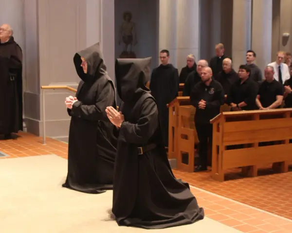Monk characteristics are evident in the solemn robes and prayerful stances of individuals in a church setting.