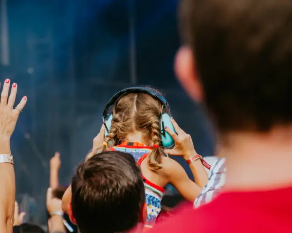Une jeune fille aux tresses bleues porte un casque anti-bruit pour contrôler le niveau sonore d'un concert.