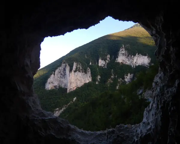 Vista dalla **grotta nera** su un monte verdeggiante con rocce bianche affioranti.