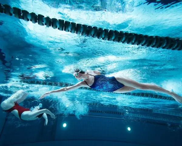 Deux nageuses en action, l'une effectuant une culbute natation, l'autre nageant le crawl sous l'eau.