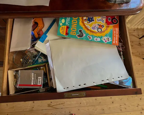 En låda fylld med pysselmaterial, papper, en bok med bondgårdstema och klistermärken, samt en burk med nålar och **påsklämmor**.