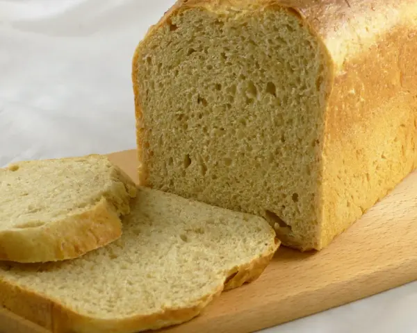 Frisch gebackenes Brot, das wie aus Buchweizen und anderen Getreidesorten gemacht aussieht, liegt auf einem Holzbrett.