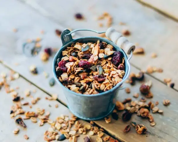 Un cubo metálico lleno de granola casera, con arándanos y semillas. ¡Perfecto para saber como hacer granola!
