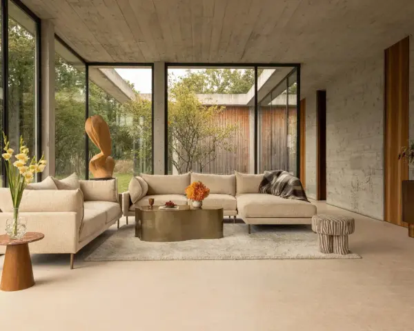 Sofá seccional beige y sillón en un salón moderno con grandes ventanales. Las combinaciones con beige crean un ambiente sereno y elegante.