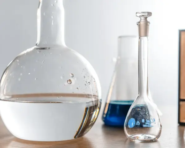 Laboratorieglas med vatten och blå vätska. Frågan om man kan dricka destillerat vatten är relevant i vetenskapliga sammanhang.