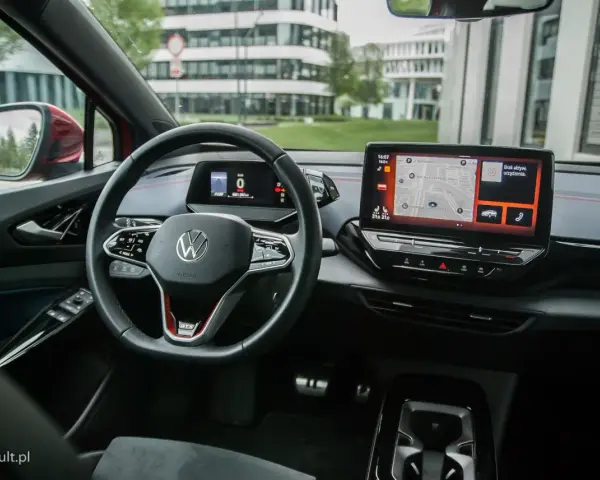 Wnętrze Volkswagena ID.4 GTX z ekranem nawigacji i cyfrowym kokpitem. Kierownica z przyciskami i oznaczeniem GTX.