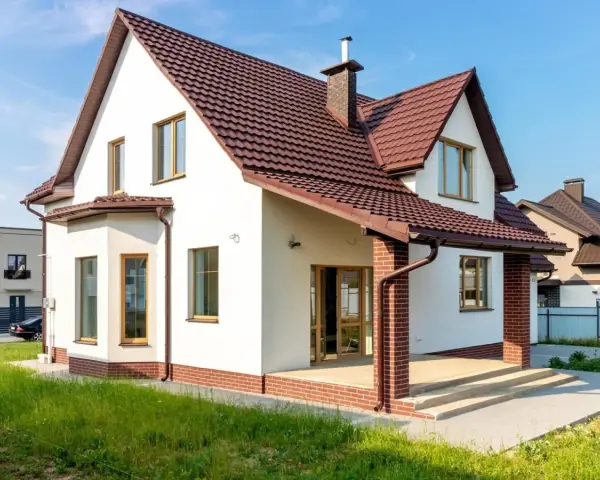 Biała elewacja z ceglanym cokołem i brązowym dachem. Klasyczne, ponadczasowe połączenie, które zawsze wygląda stylowo, pokazując najmodniejsze kolory elewacji.
