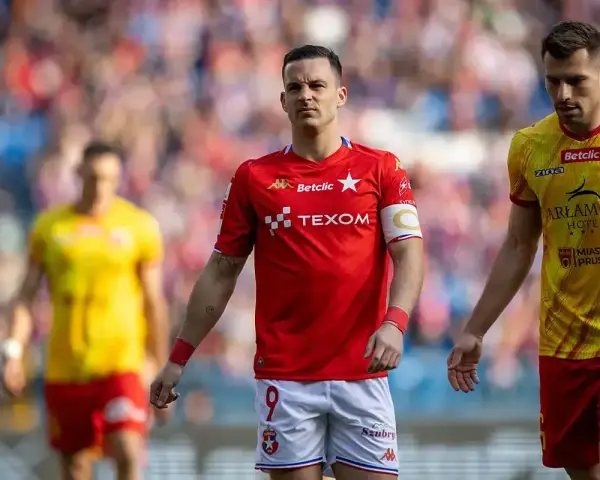 Piłkarze Wisły Kraków i Znicza Pruszków na boisku. W czerwonych strojach zawodnicy Wisły, w żółtych Znicza.