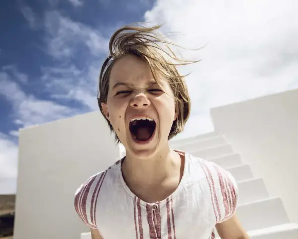 Kind schreit laut, Haare wehen im Wind. Ein Moment, der an einen affektive Dysregulation test erinnert.