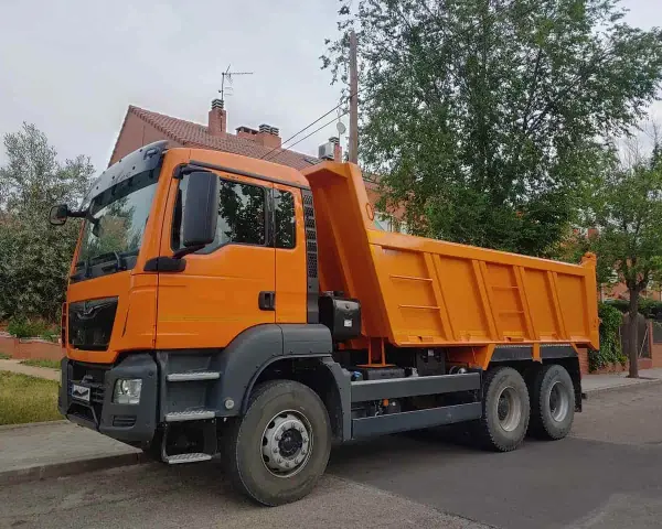 Pomarańczowy wywrotka c1 stoi na ulicy, gotowa do pracy.