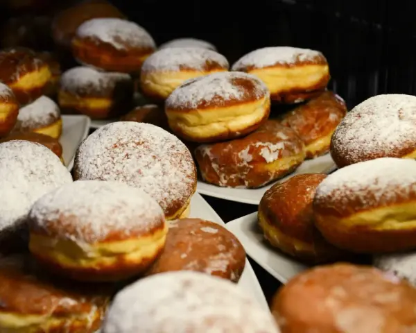Puszyste pączki z piekarnika, niektóre oprószone cukrem pudrem, inne błyszczące od lukru. Idealne na tłusty czwartek!