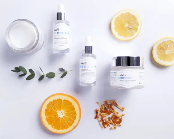 Hudvårdsprodukter från Klairs med C-vitaminserum och en kräm med e-vitamin hud för lyster. Citron- och apelsinskivor som dekoration.