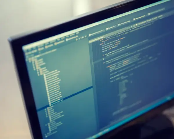 Programista pracuje nad kodem PHP. Format komputera pozwala na szybkie tworzenie i edycję skomplikowanych projektów.