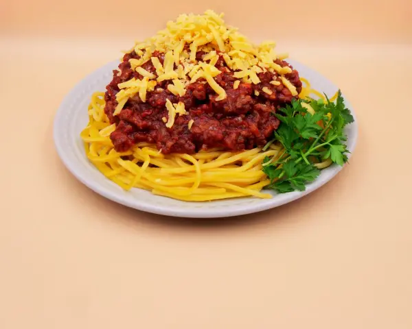 Prosty przepis na spaghetti z mięsem mielonym: makaron, sos boloński, starty ser i natka pietruszki na talerzu.