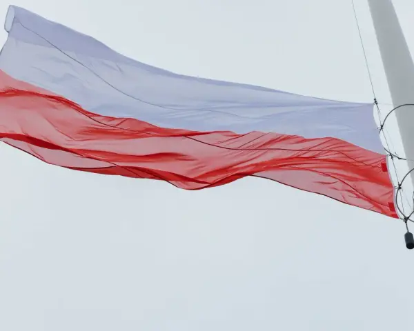 Biało-czerwona flaga na maszcie powiewa na wietrze, symbolizując dumę i wolność.