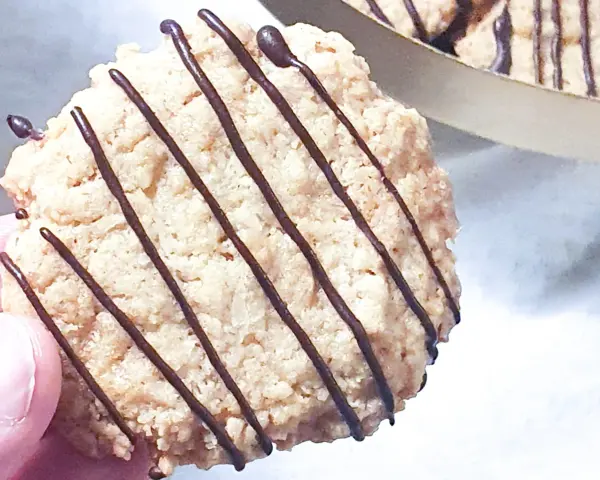 En hand håller en chokladglaserad havrekaka. Perfekt för ett enkelt havrekakor recept.