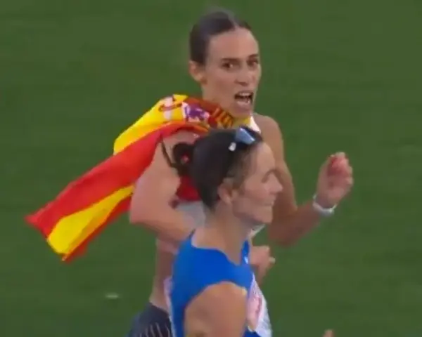 Laura García Caro celebra su victoria en atletismo, ondeando la bandera española con orgullo.
