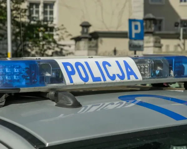 Niebieskie światła policyjne i napis "POLICJA" na dachu radiowozu. Uważaj na przegląd, bo czeka mandat za brak przeglądu.