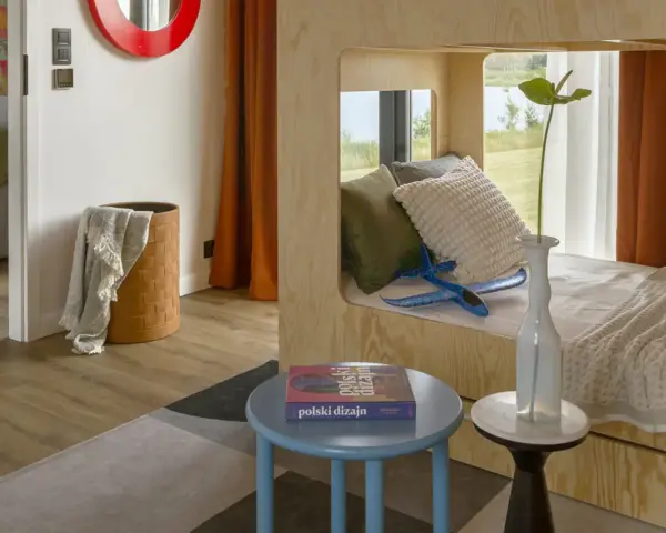 Un lit superposé dortoir maternelle en bois, avec des coussins douillets et un avion bleu pour l'aventure.