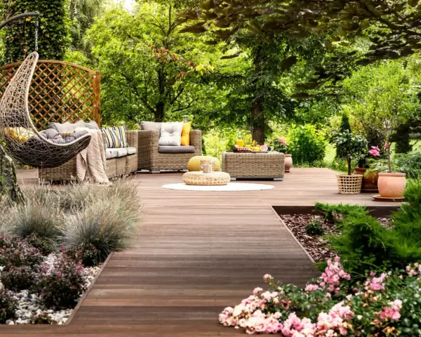 Un rincón acogedor con muebles de mimbre, una hamaca colgante y flores, ideal para disfrutar de pequeños jardines.