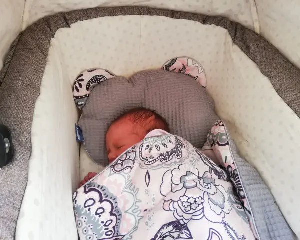 Malutkie dziecko śpi w wózku, otulone kolorowym kocykiem. To pierwszy spacer, czas na drzemkę.