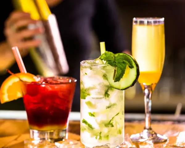 Mojito na białym rumie kontra Mojito na ciemnym. Trzy drinki: czerwony z pomarańczą, zielony z ogórkiem i żółty.